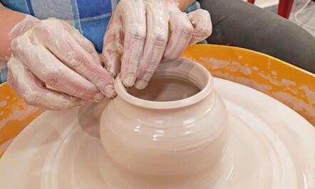 A close-up shot of a participant pulling a pot on potter's wheel at Sona Pottery