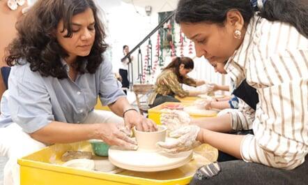 Sona Srivastava, the Founder and Lead Ceramic Artist at Sona Pottery guiding a participant on how to shape a mug on potter's wheel