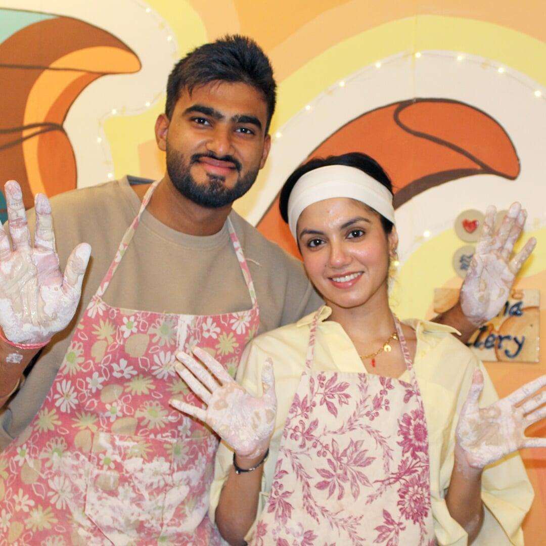 A girl and boy happily posing after experiencing a Pottery Workshop. Their hands are smudged with clay